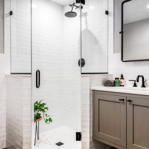 Four Brothers hall bathroom renovation in Alexandria, VA, with a glass-enclosed shower, white tile, and gray vanity.