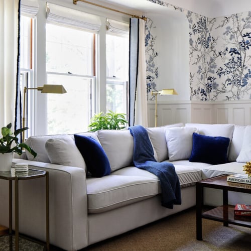 Family room renovated by Four Brothers Design + Build in Massachusetts Heights, Washington, DC, with blue botanical wallpaper above white wainscoting and a white sectional.