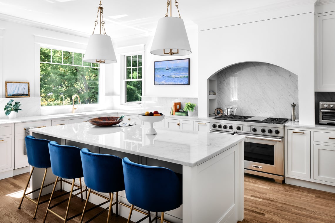 Massachusetts Heights, DC, kitchen remodel by Four Brothers Design + Build with white cabinetry, blue island stools and an arched range hood.