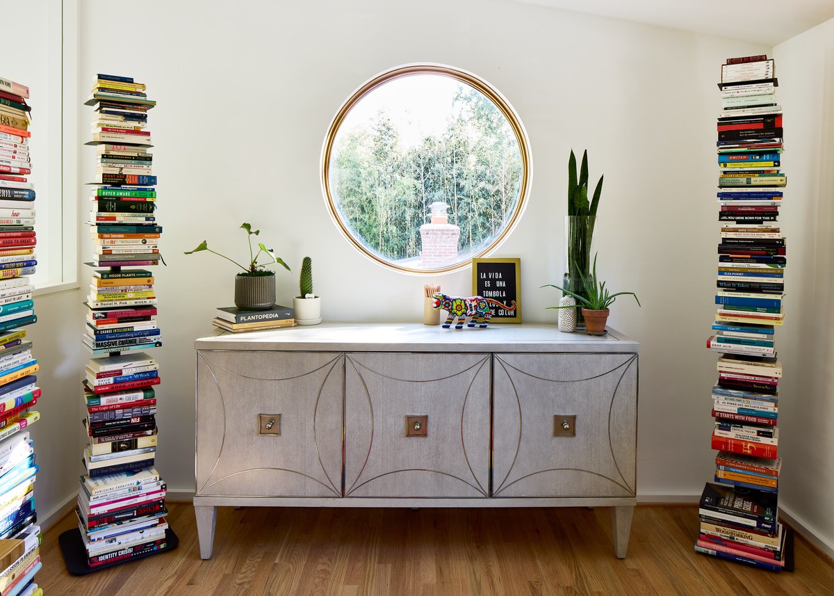 Four Brothers Design + Build home renovation in Chevy Chase, Maryland, featuring a round window, sculptural cabinet, indoor plants, and floor-to-ceiling book towers.