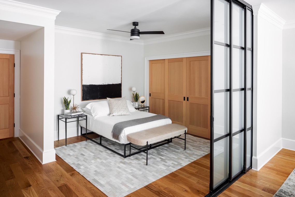 Bedroom by Four Brothers Design + Build in a Logan Circle, DC, row home with wood closet doors and a black-framed frosted-glass sliding partition.